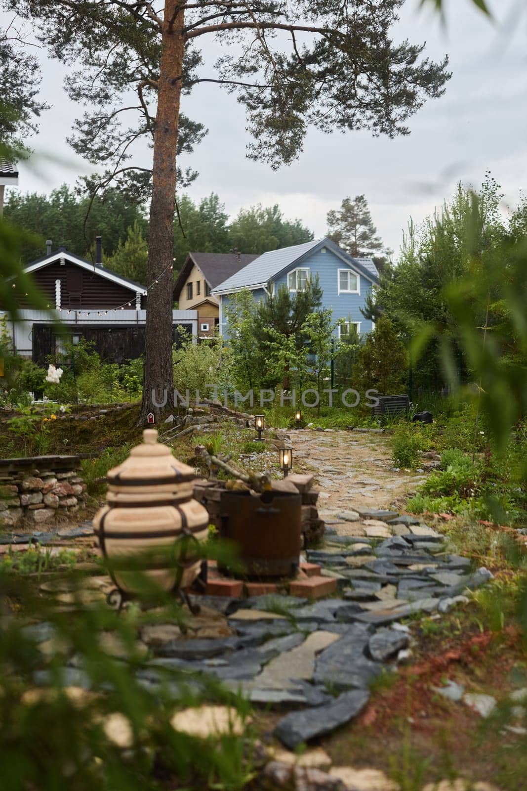A tranquil garden path with stone tiles and greenery, alongside charming houses in the distant background