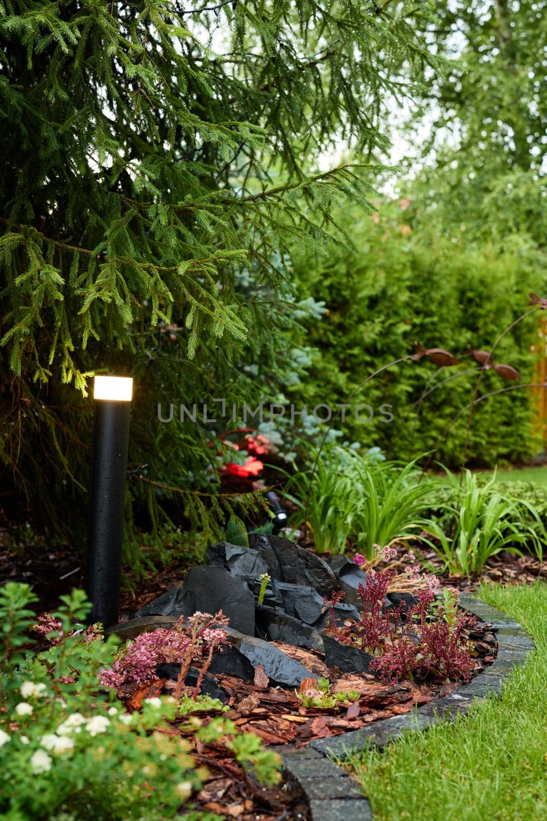 A beautiful garden scene that features exquisite landscaping, ambient lights, and vibrant, lush greenery all around