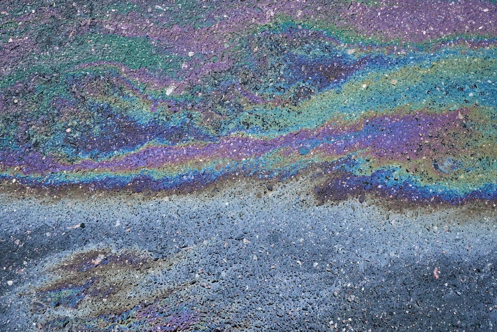 Vivid oil stain on an asphalt road, creating an abstract background.