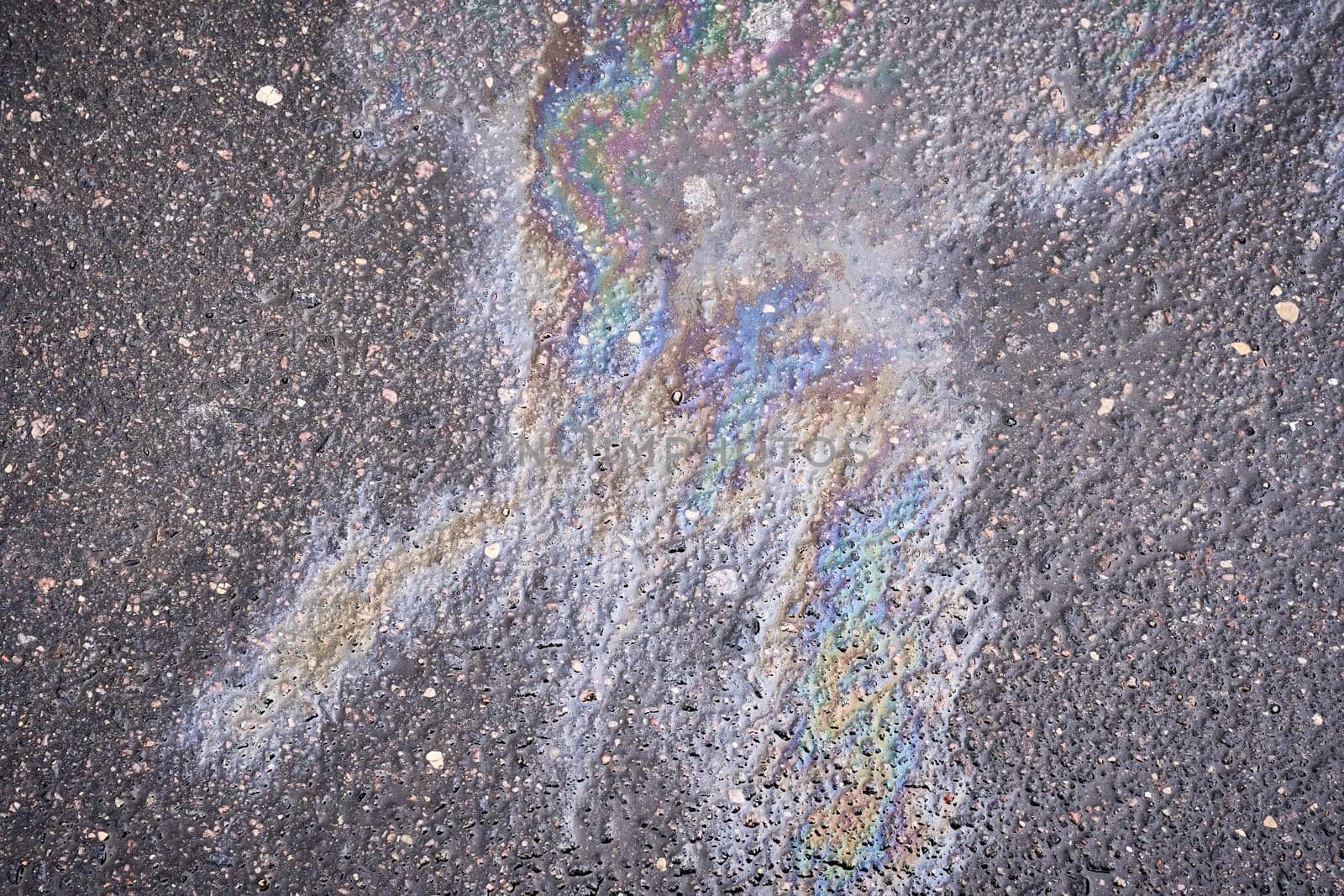 Circular patch of vibrant gasoline or oil spill on the roadway