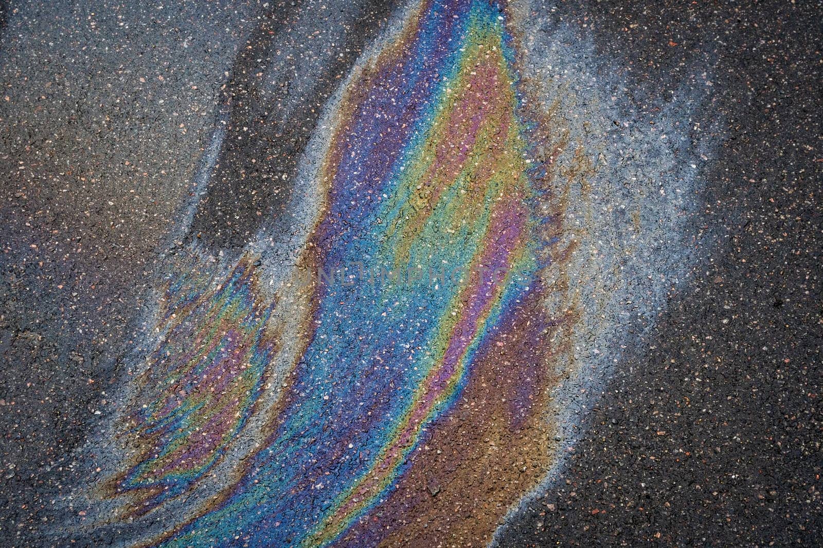 A multi-colored oil slick on an asphalt driveway that shimmers with all the colors of the rainbow