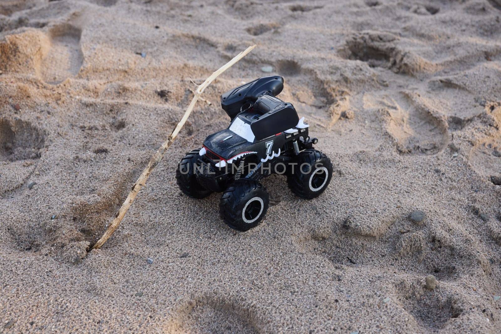 A sleek black remotecontrolled monster truck racing across sandy terrain, ideal for exhilarating outdoor adventures