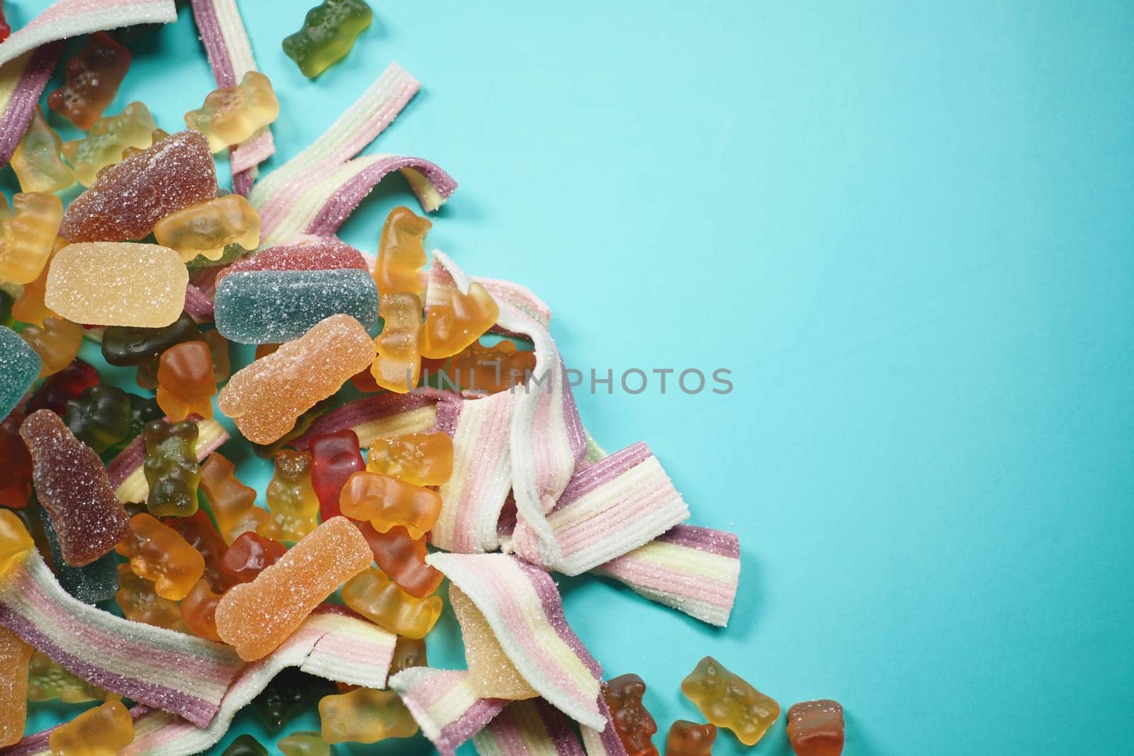 A colorful mix of gummy candies scattered on a bright blue surface, creating an appealing treat
