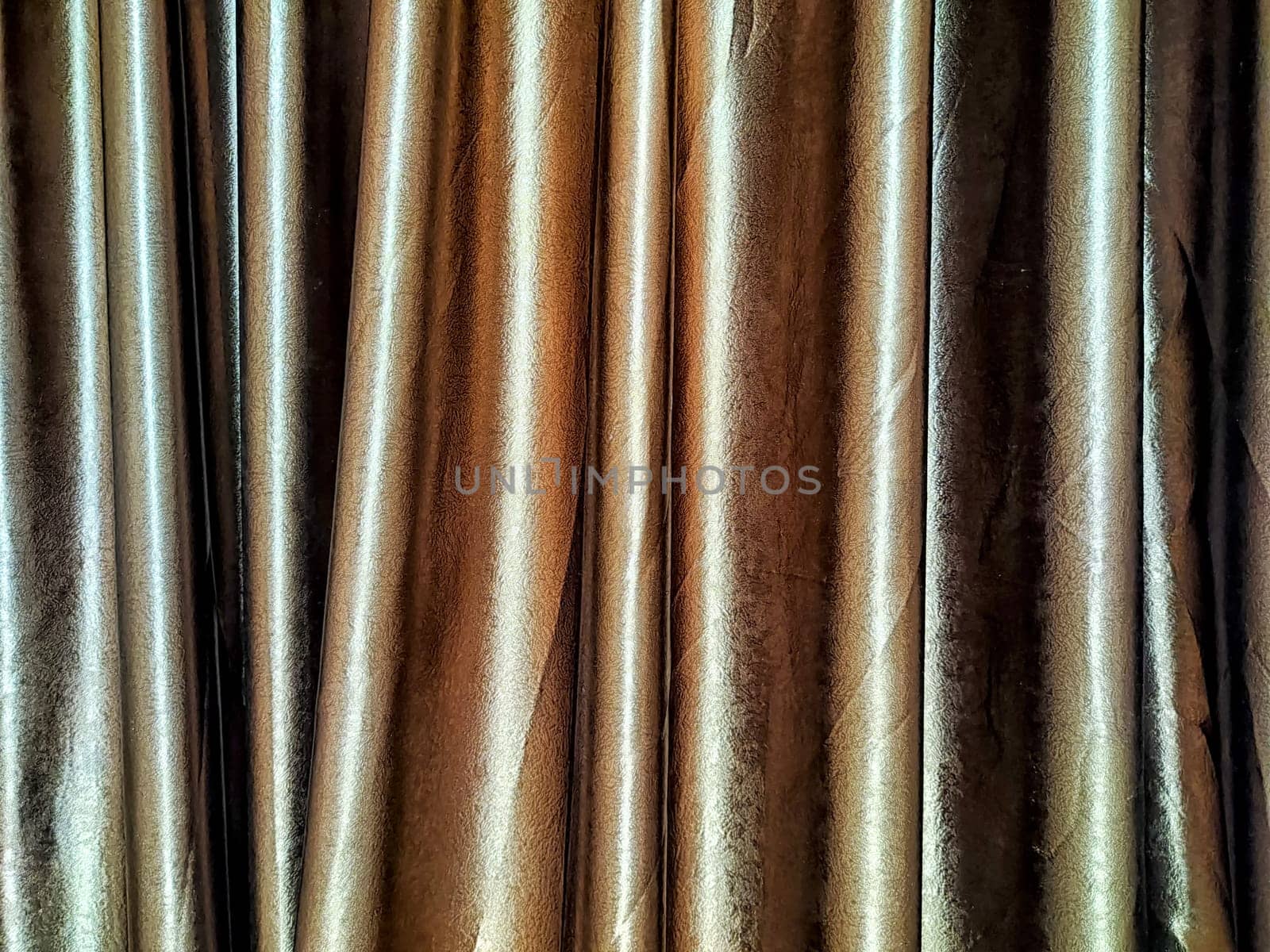 Rich brown silk curtains cascade gently, adding texture and warmth to the ambiance of a stylish room through soft, elegant folds.