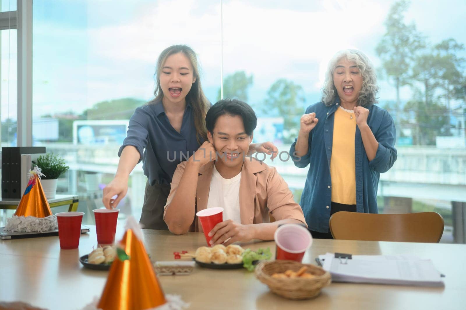 Cheerful group of colleagues enjoying snacks and drinks during a lively office party.