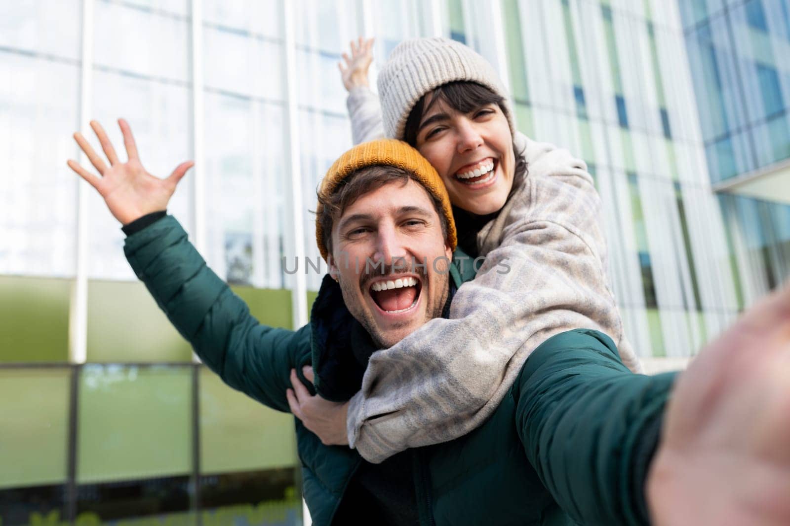 Cheerful couple taking a selfie while enjoying a playful moment outdoors looking at camera