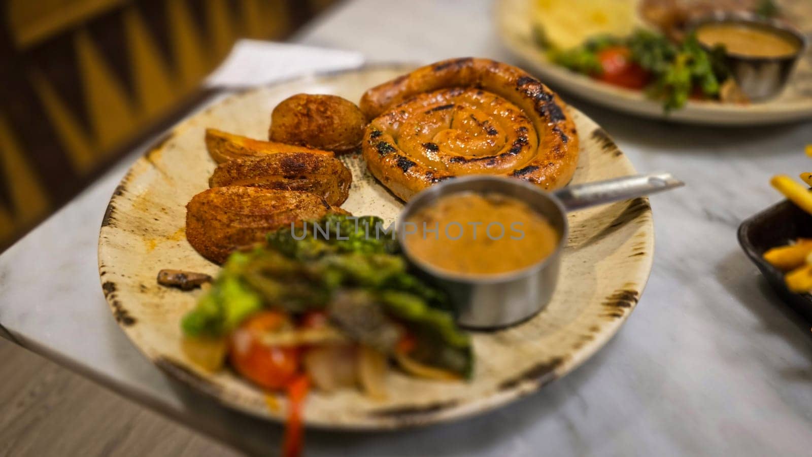 mouthwatering German worst curled up cumberland sausage meal featuring a grilled sausage, loaded cheese fries, and fresh vegetables served on a rustic plate. Perfect for dinner lovers appreciating hearty and flavorful dishes.