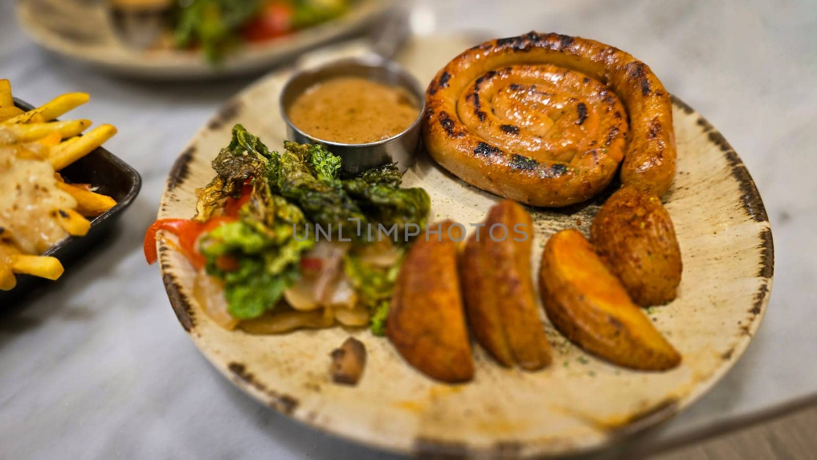 mouthwatering German worst curled up cumberland sausage meal featuring a grilled sausage, loaded cheese fries, and fresh vegetables served on a rustic plate. Perfect for dinner lovers appreciating hearty and flavorful dishes.