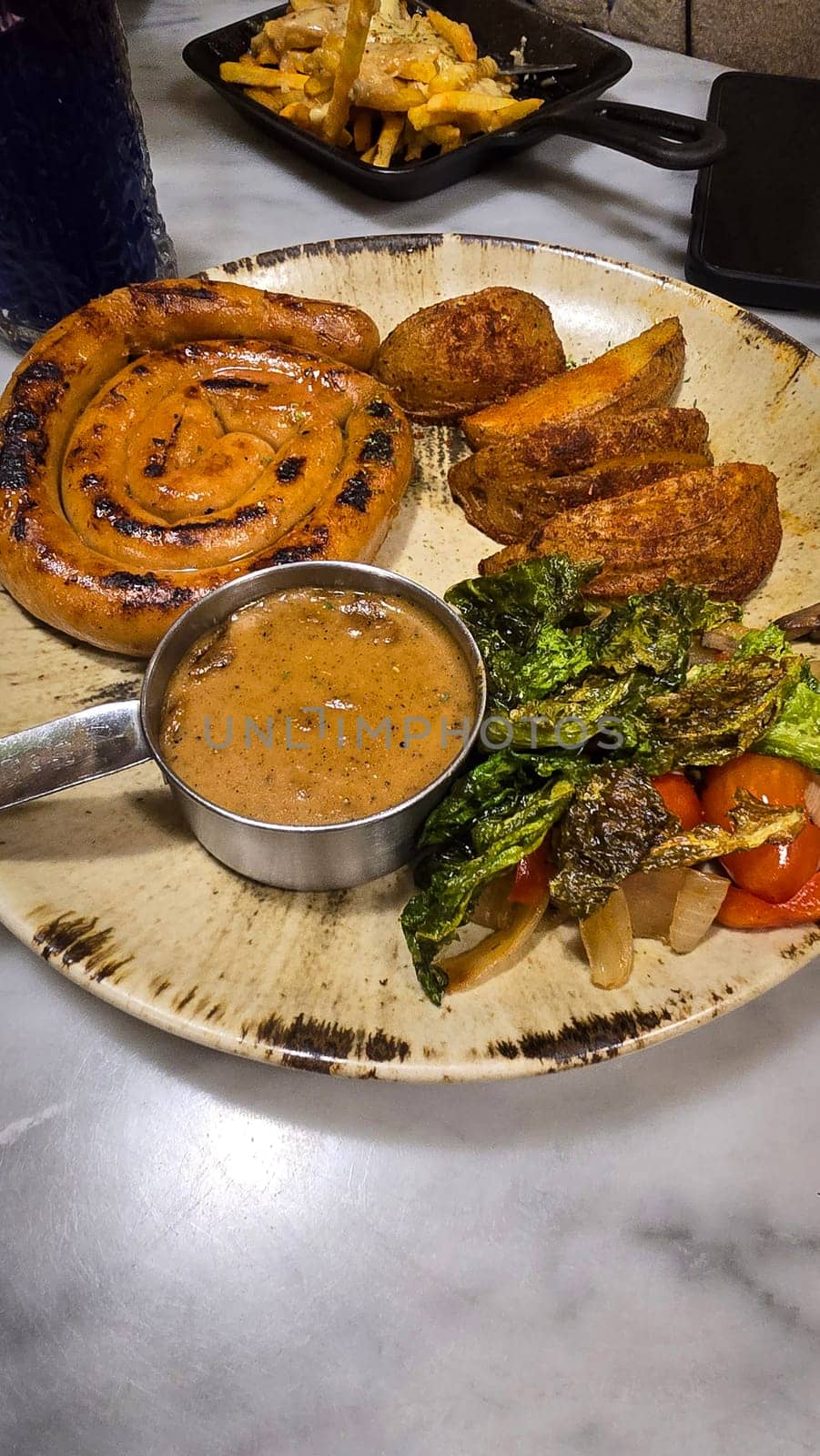 mouthwatering German worst curled up cumberland sausage meal featuring a grilled sausage, loaded cheese fries, and fresh vegetables served on a rustic plate. Perfect for dinner lovers appreciating hearty and flavorful dishes.