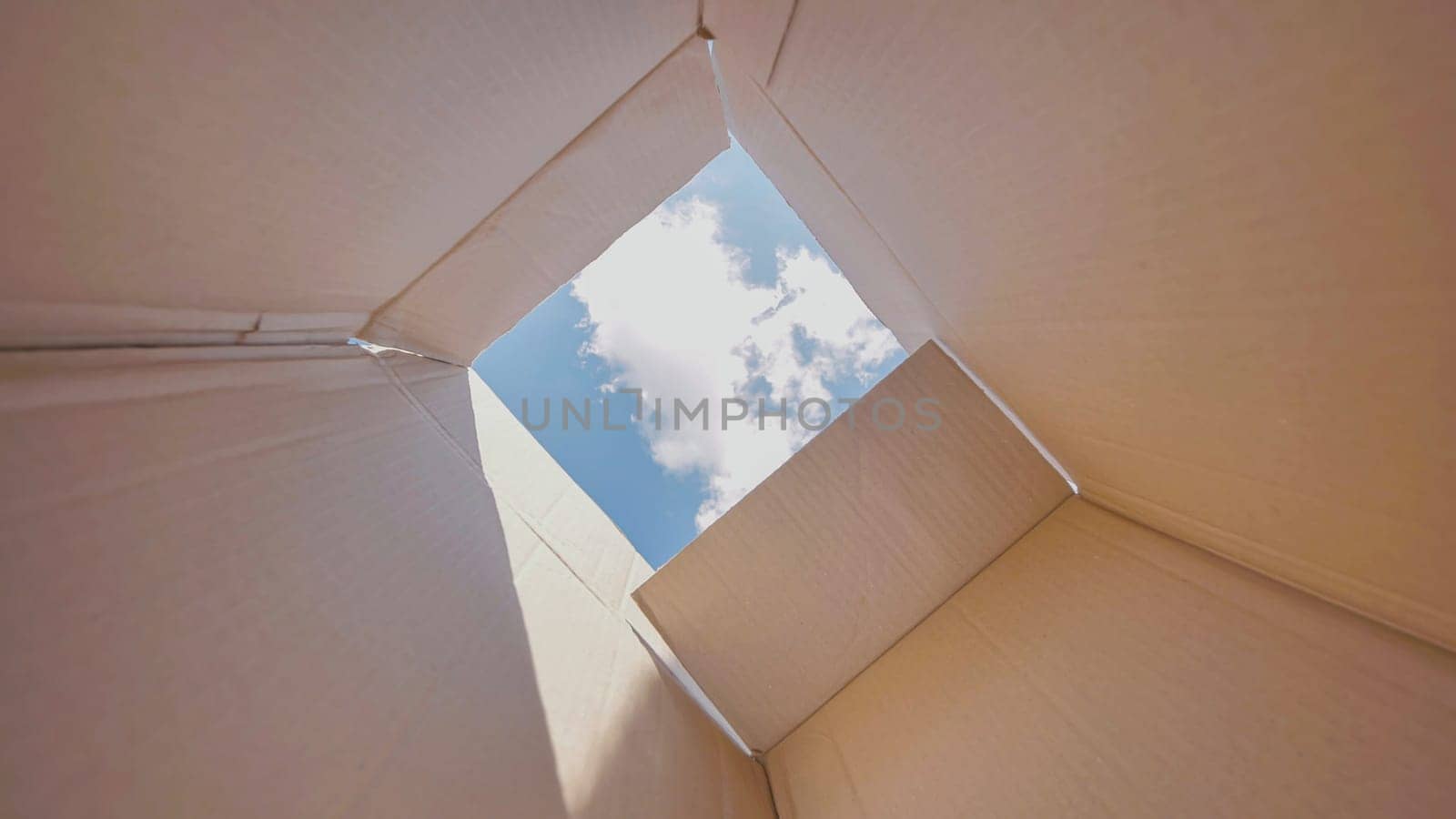 Open cardboard box is revealing a blue sky with some clouds, suggesting freedom, hope and new possibilities.