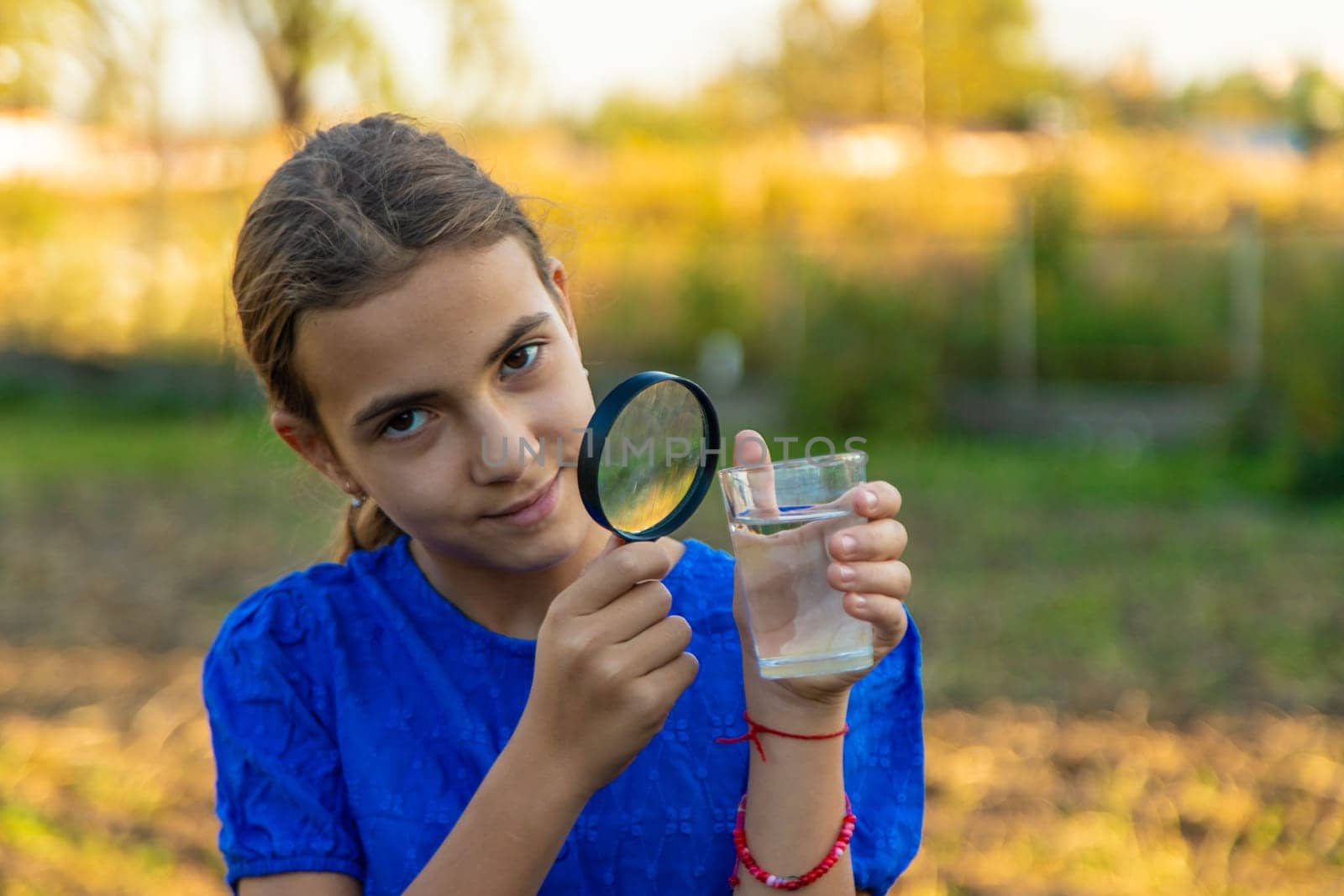 A child looks at water through a magnifying glass. Selective focus. kid.