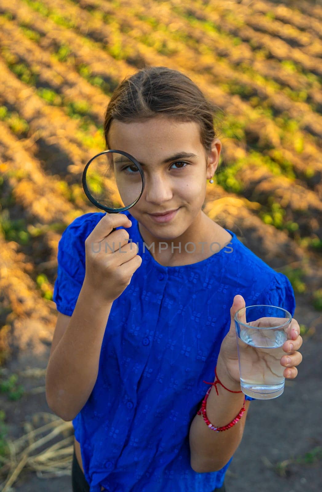 A child looks at water through a magnifying glass. Selective focus. kid.