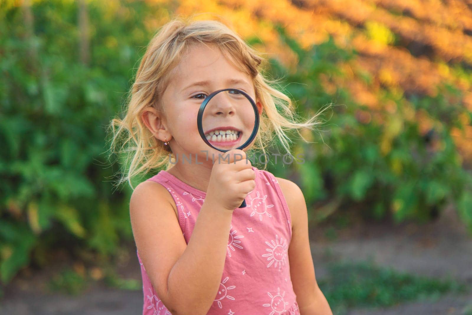 A child looks through a magnifying glass in nature. Selective focus. Kid.