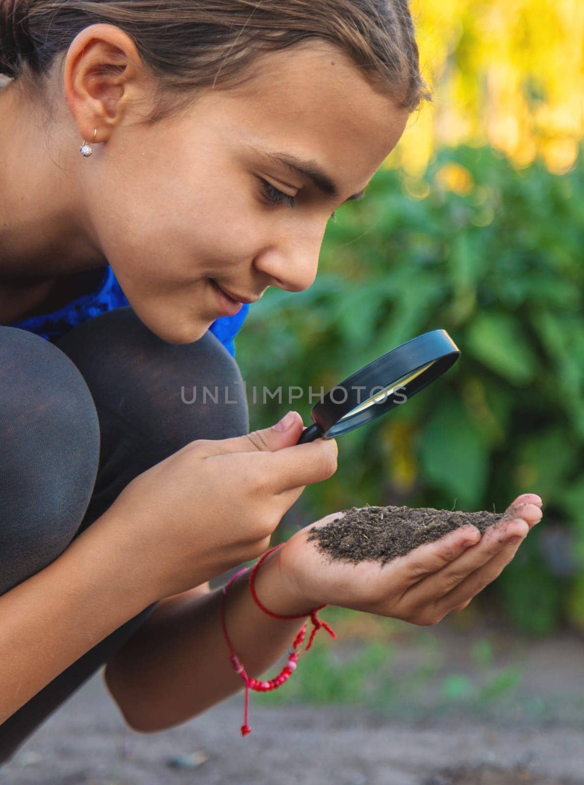 A child looks at the soil through a magnifying glass. Selective focus. Kid.
