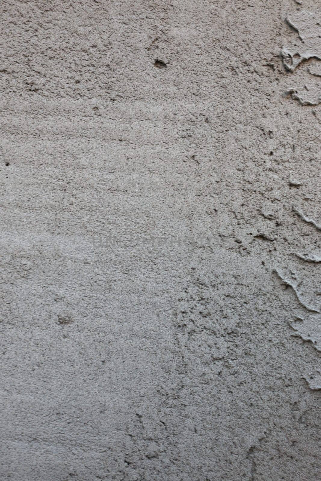 Vertical Close-up photo of old abandoned plaster on a concrete wall.