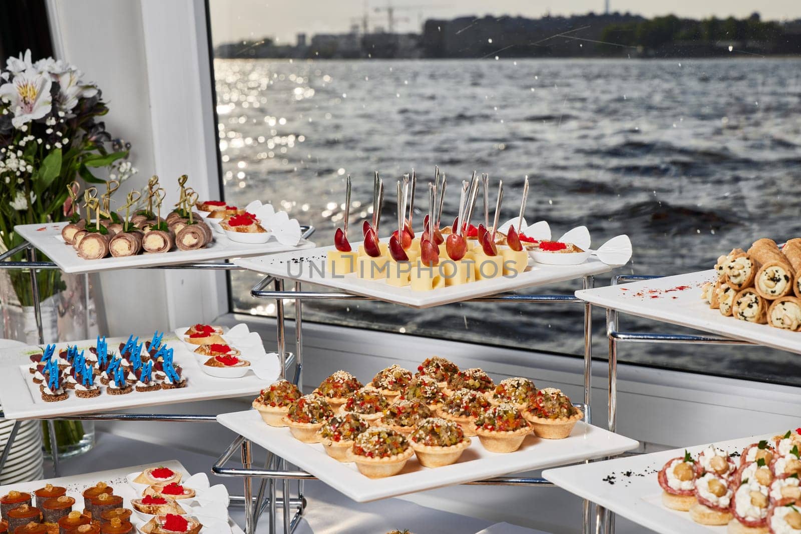A beautifully arranged buffet that features a wide variety of delicious appetizers alongside a scenic water view