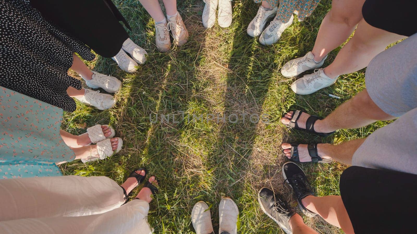 Group of friends is standing on the grass in a circle, celebrating their graduation