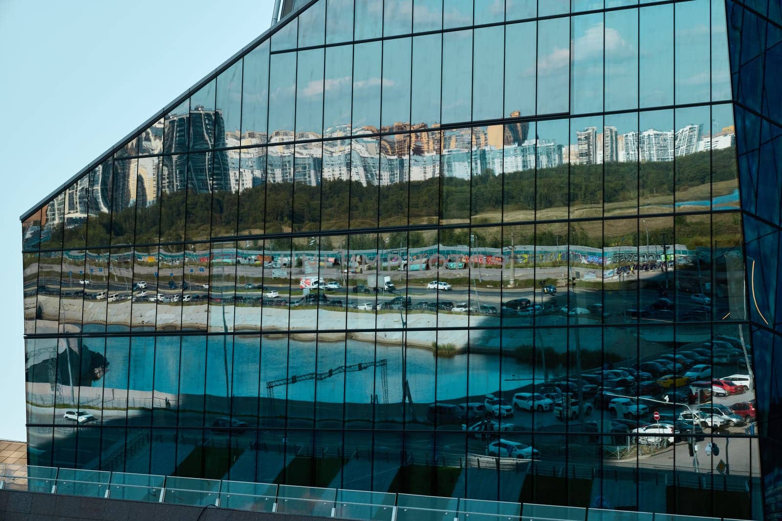 A striking reflection of a vibrant cityscape appears on a sleek glass building showcasing modern architecture
