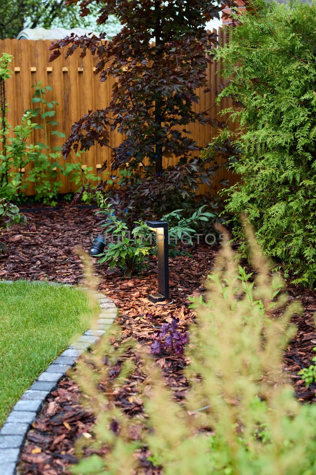A modern garden with sleek lighting, vibrant greenery, and decorative landscaping that enhances its charm