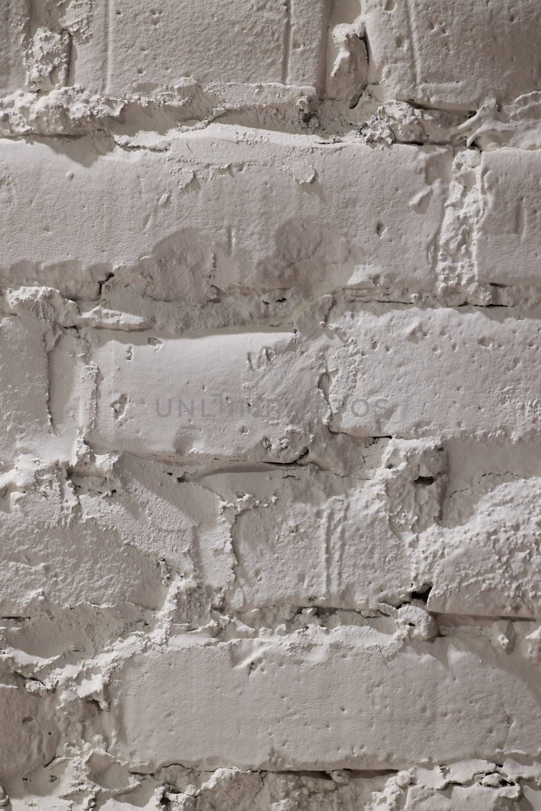This is a detailed closeup image of a weathered white brick wall showcasing its subtle textures and unique patterns