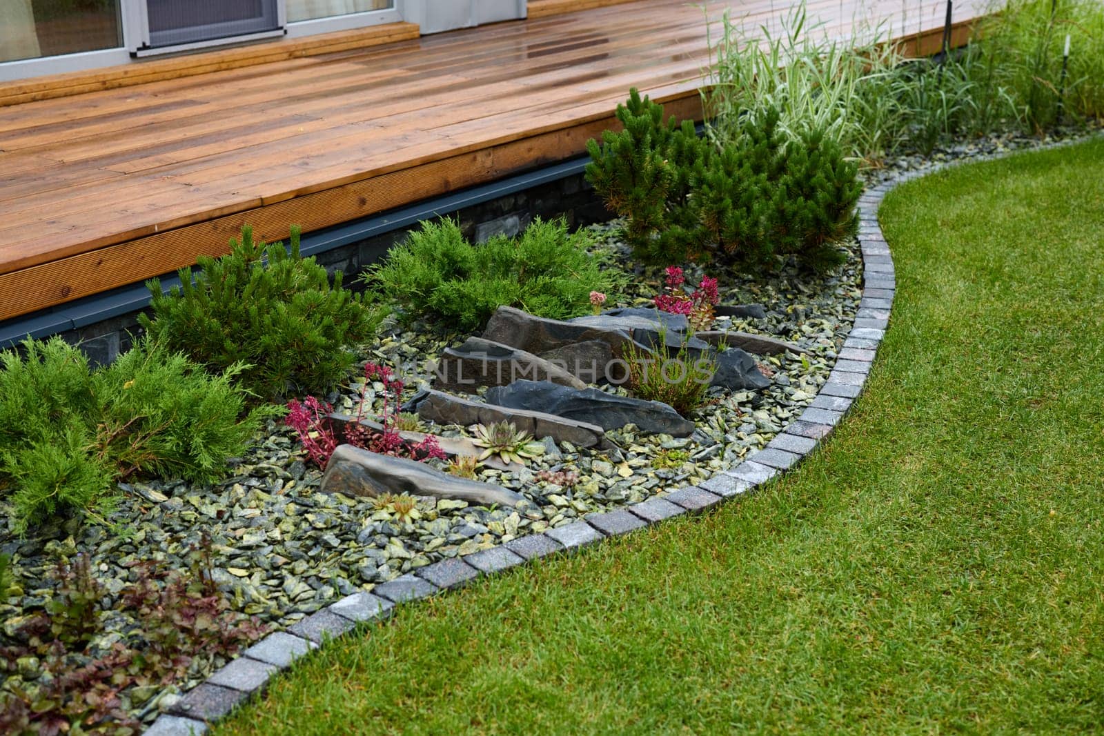 A beautifully arranged garden with elegant stones, vibrant plants, and a manicured lawn creating a serene retreat