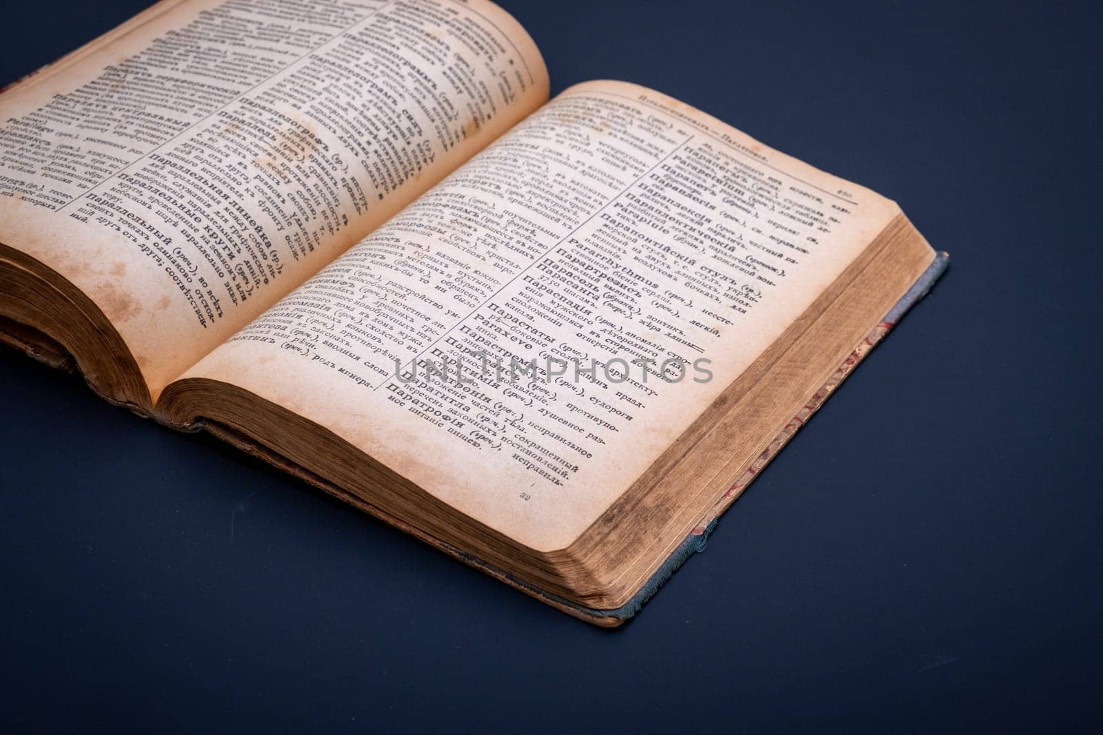 Close-up of an open antique dictionary against a dark background. Selective focus.