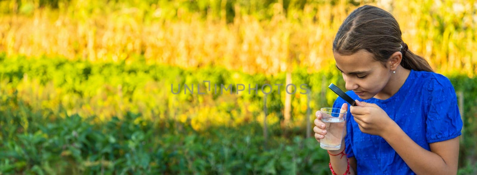 A child looks at water through a magnifying glass. Selective focus. kid.