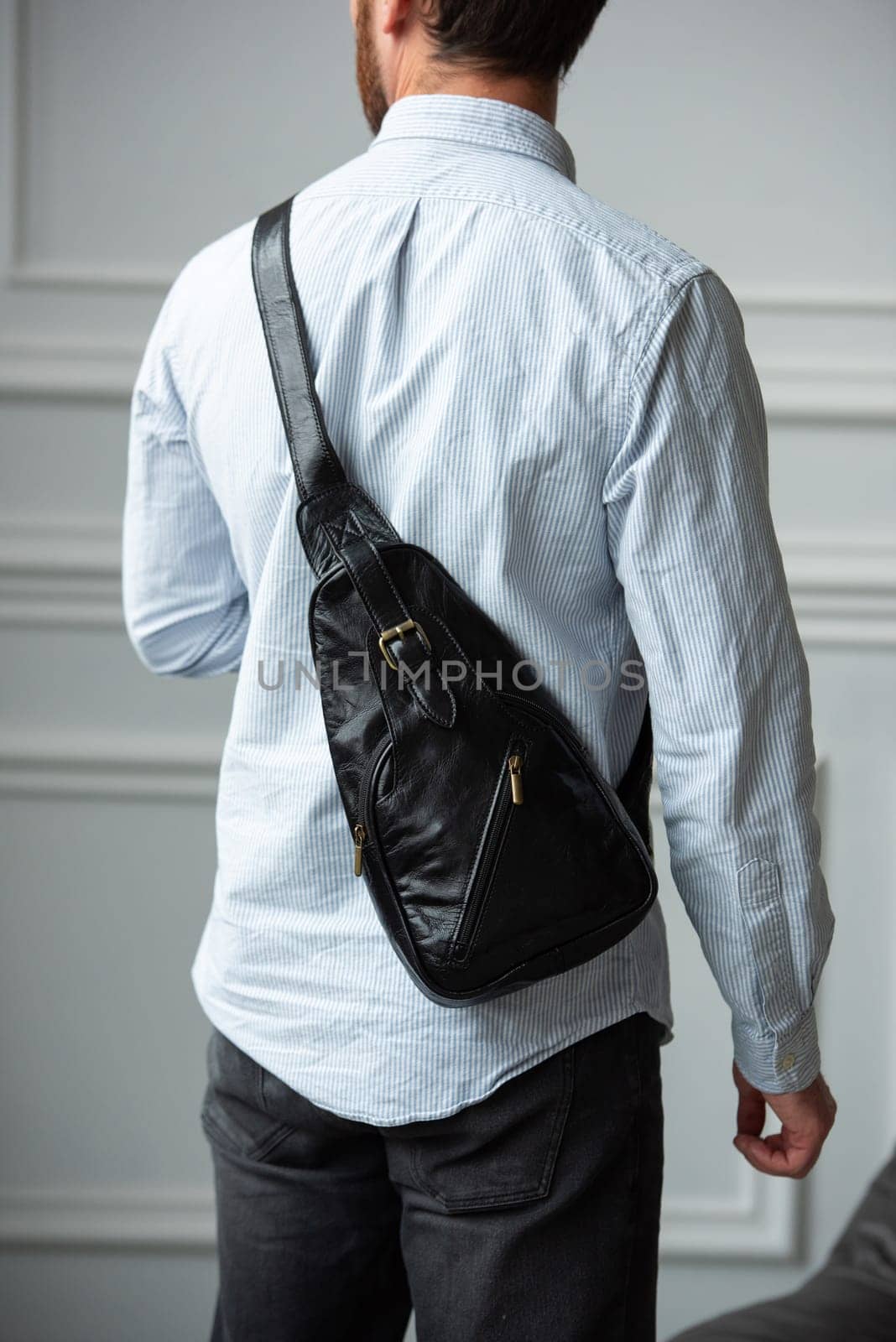 A man in a shirt with holding a black bag on his shoulder