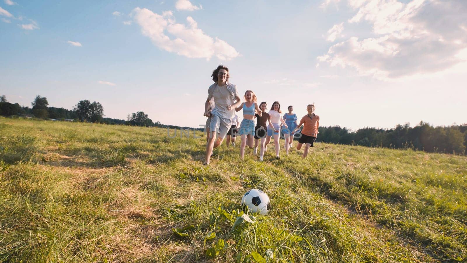 Graduates joyfully play soccer on a sunlit field, marking their accomplishments and looking forward to a bright future with friends