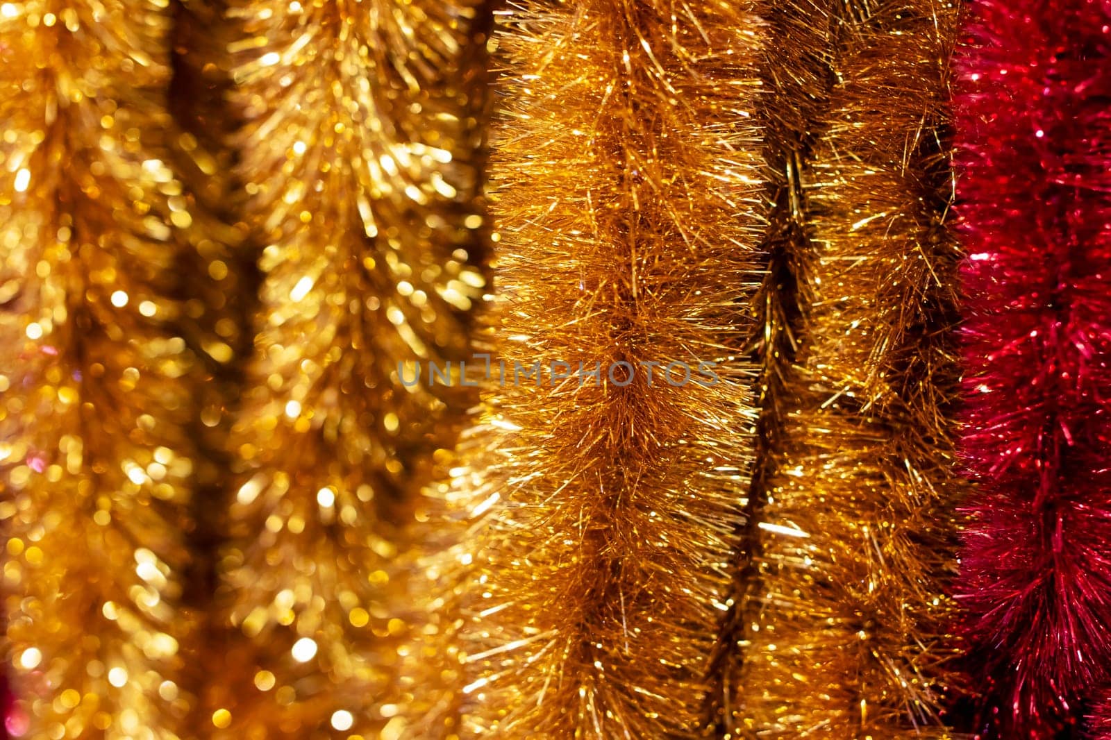 A detailed and closeup view of a vibrant bunch of glimmering gold and rich red tinsel, illustrating its intricate design and colors