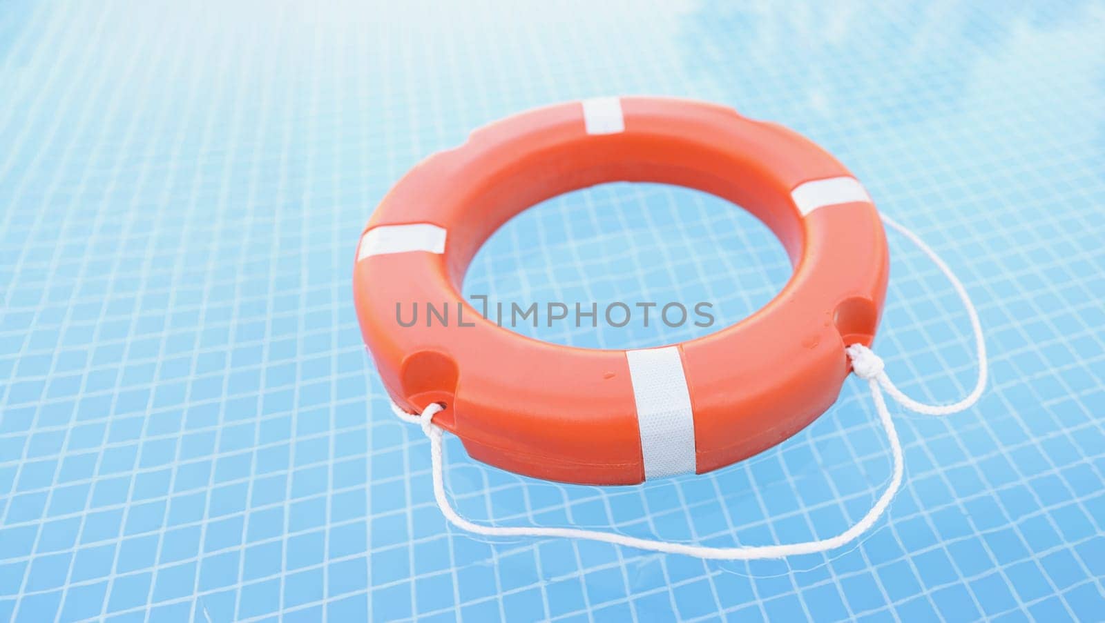 Red lifebuoy in the pool, blue water, close-up. Drowning assistance, safety when learning to swim, protection