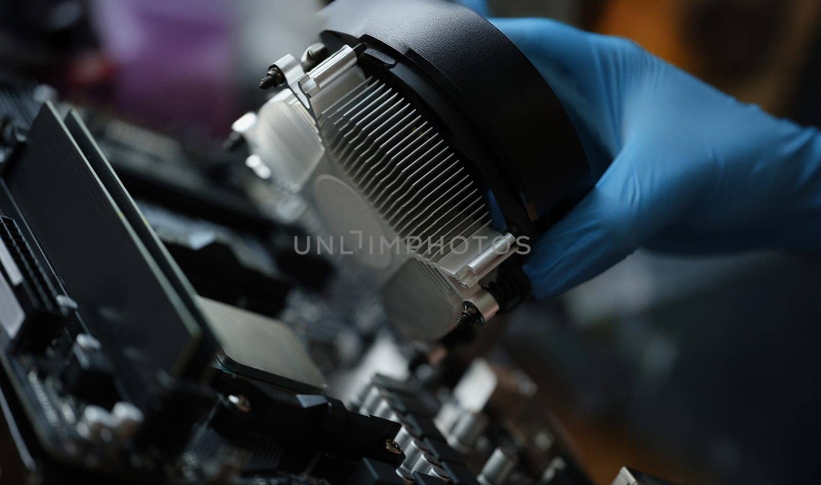 A hand in a glove installs a new cooler for a pc, close-up. Cooling system in the computer, repair, upgrade, cleaning from dust
