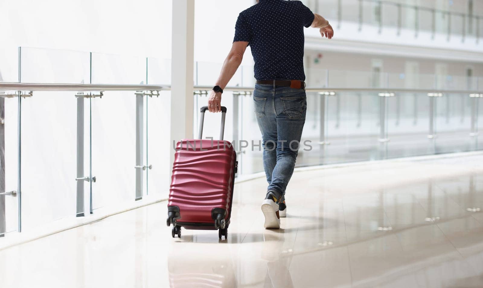 A man carrying a suitcase at the airport terminal, close-up, rear view. Travel, arrival at the station, passenger luggage