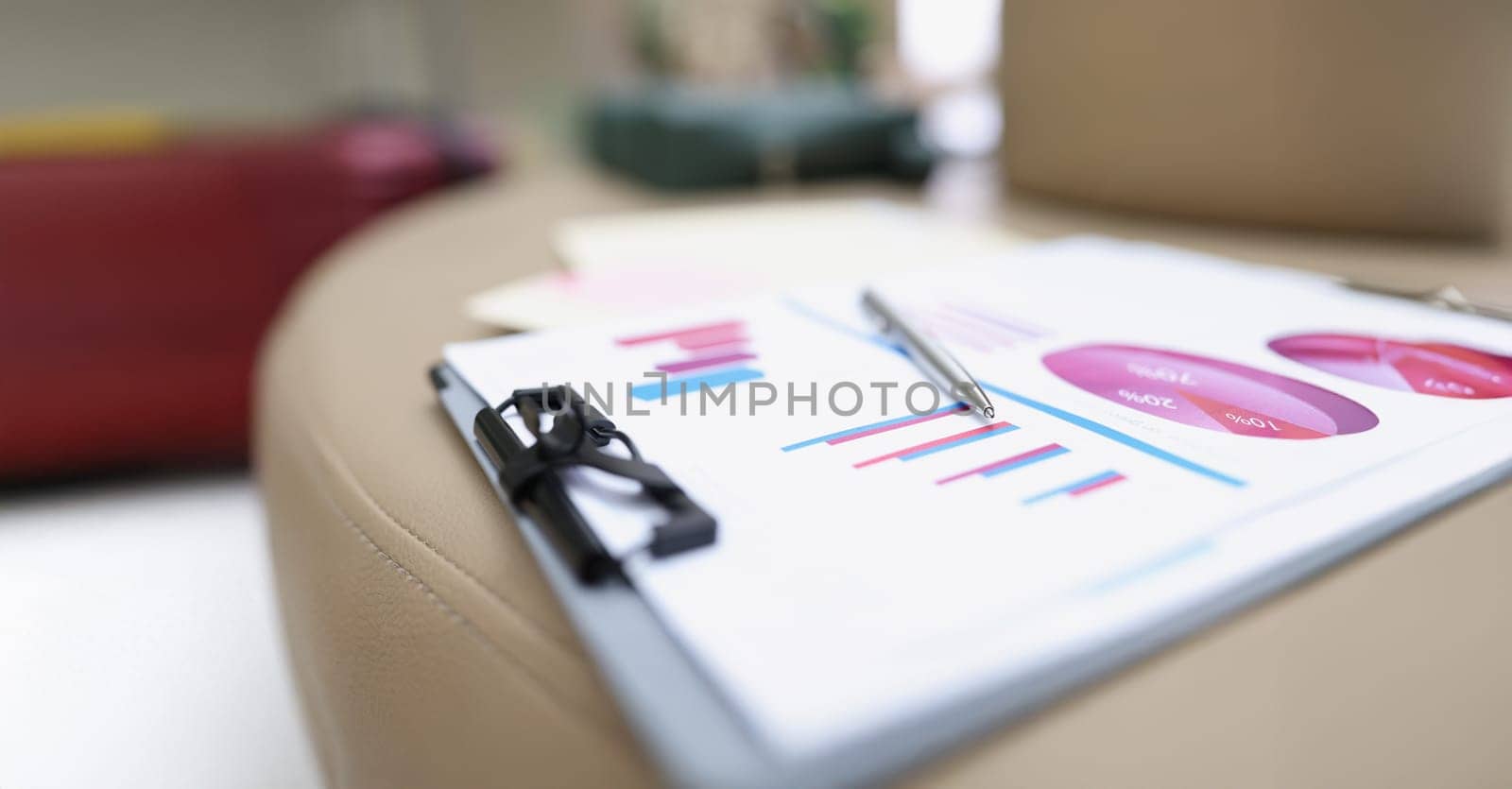A folder with documents lies on a leather surface, close-up, blurry. Audit preparation, color chart and graph on paper