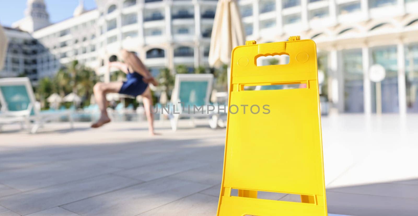 Yellow plastic wet floor warning signs on the background of a falling man, close-up, blurry. Traumatic slippery
