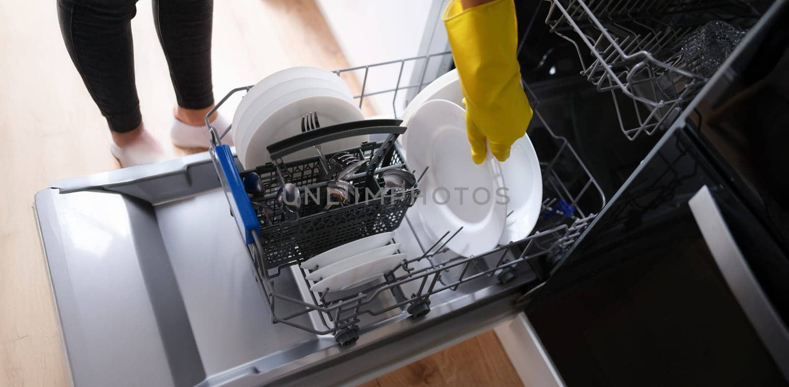 A woman takes out clean dishes from the dishwasher, close-up. Cutlery washing, household appliances, housework