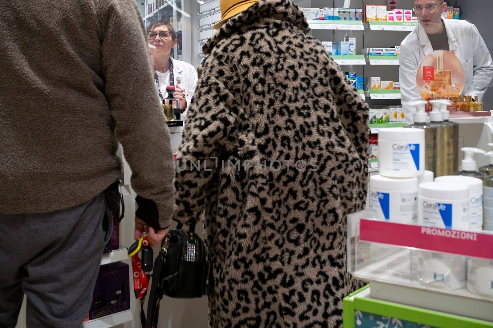 Cremona, Italy - November 20th 2024 Italian customers buying medicine and cosmetics, having a conversation with pharmacist and chemist in a pharmacy in cremona, italy