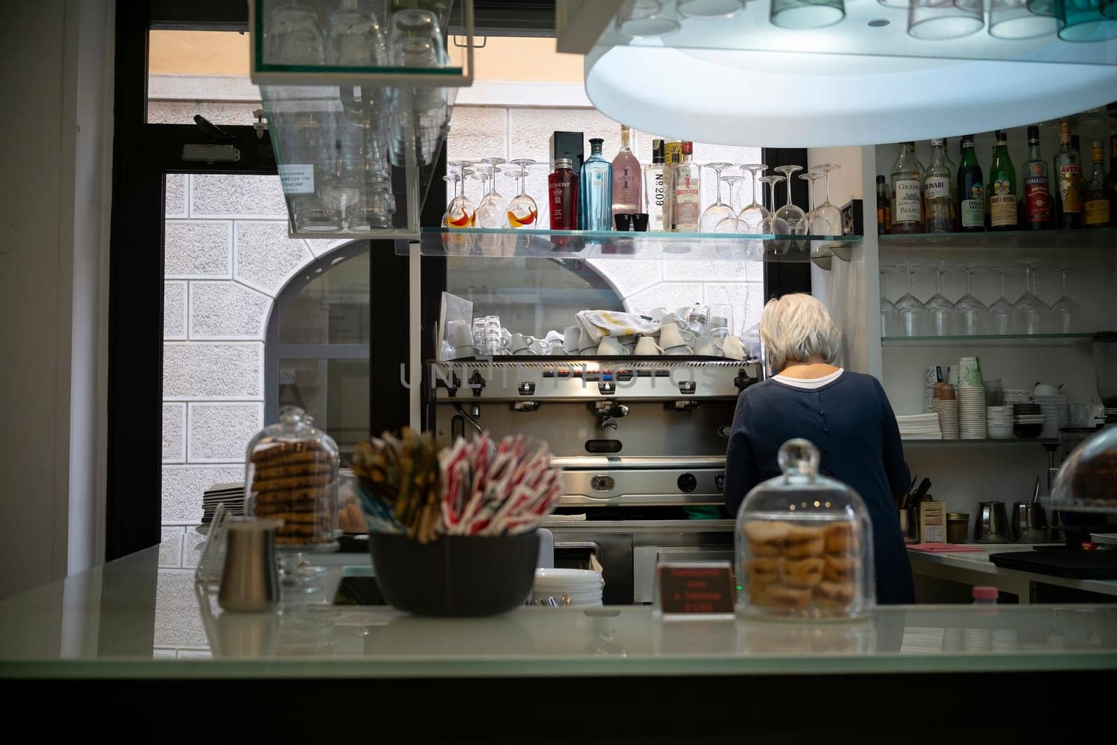 Cremona, Italy - November 20th 2024 Barista working behind the counter in a typical cafe in cremona, italy, getting ready to serve customers