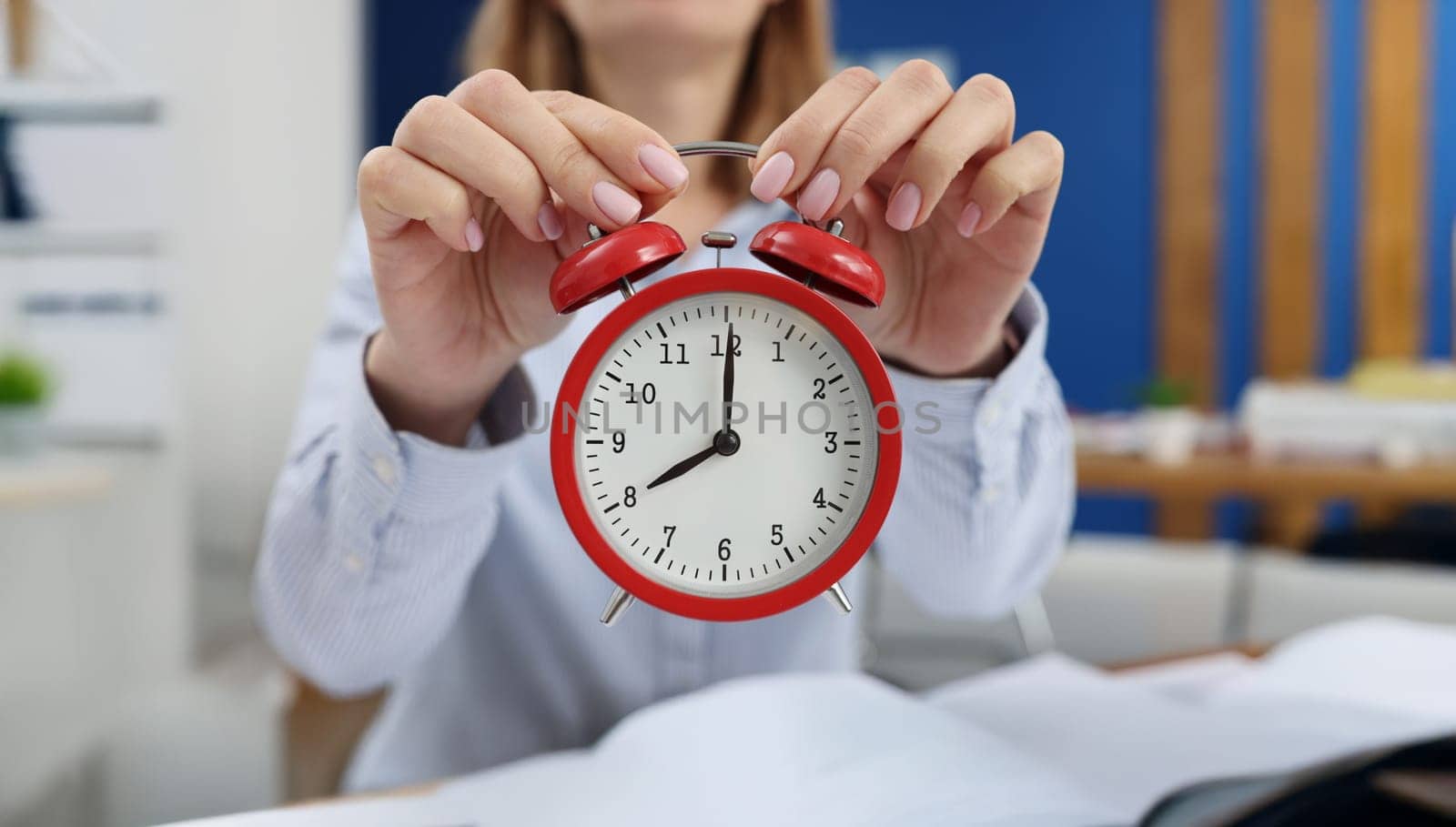 Woman holding a red alarm clock, close-up, blurry. Concept of day planning, meeting deadlines, productive morning