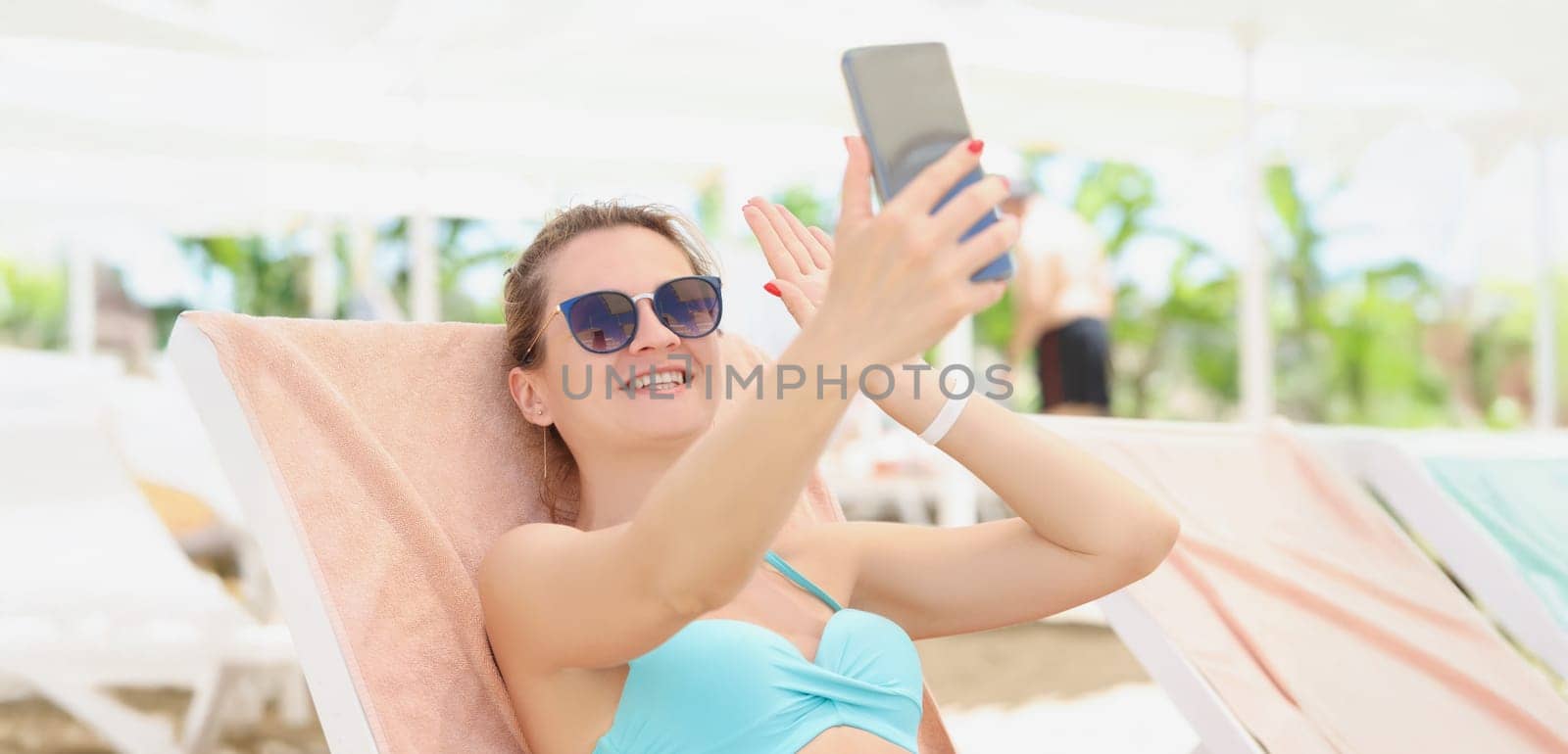 Happy woman in a swimsuit makes a selfie, close-up. Photo on vacation by the pool, summer vacation in the hotel complex