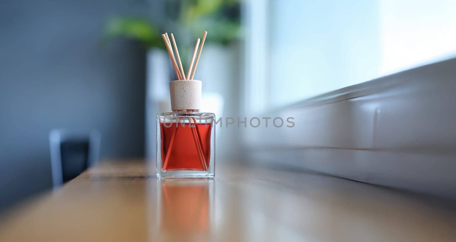 Bamboo sticks fragrance for the room stands near the window, close-up, blurry. Spread the scent. Aromatherapy