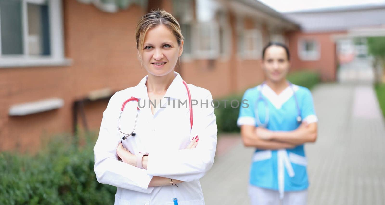 Woman doctor and nurse stand near the clinic, close-up, blurry. Rehabilitation center staff for alcoholics