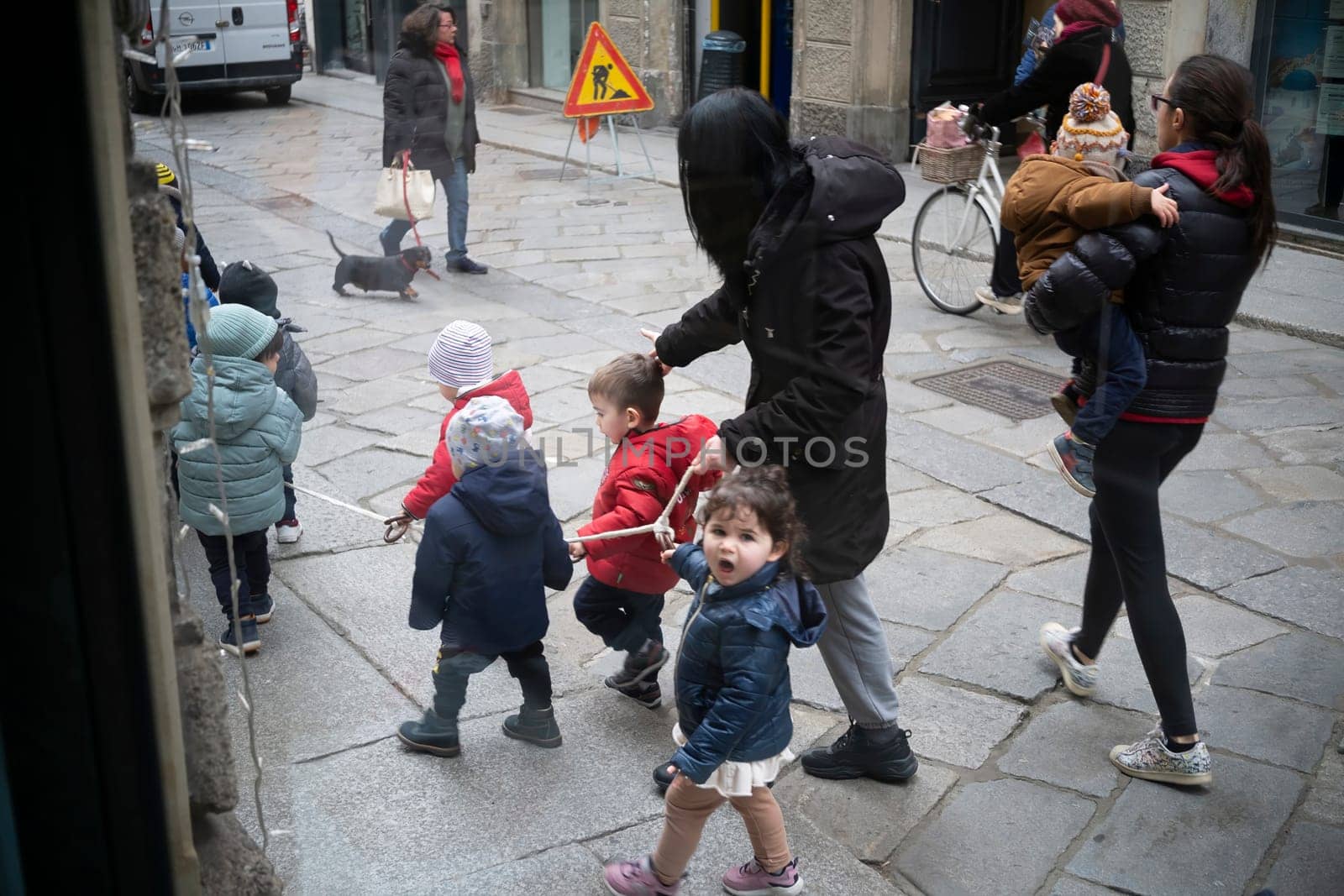 Cremona, Italy - November 20th 2024 Group of preschoolers walking on a rope held by their teacher in cremona, italy, showcasing a playful outdoor activity