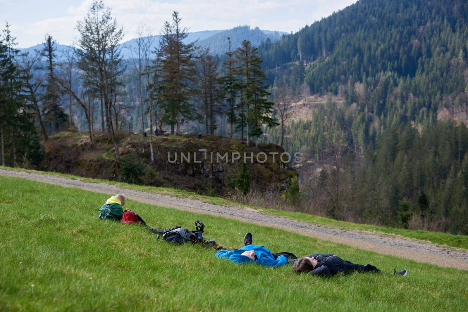 Tired hiker in blue resting lying and relaxing on the top of a high mountain. Hiker resting lying on the grass in a valley of a high mountain