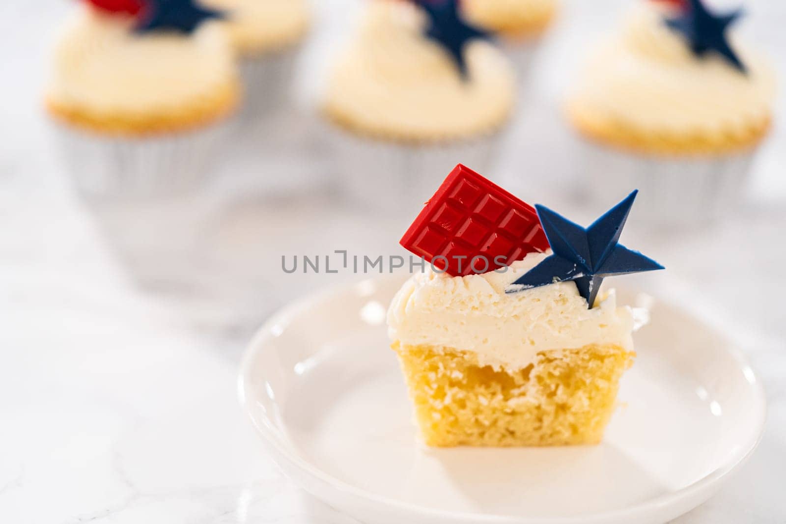 Sliced lemon cupcakes with lemon buttercream frosting, and decorated with patriotic blue chocolate star and red mini chocolate.