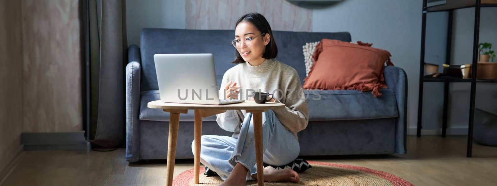 Portrait of beautiful young woman professional, working on remote from home, freelancing with her laptop, video chats, drinks coffee by Benzoix