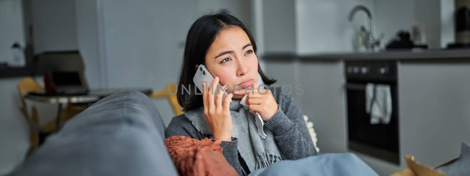 Portrait of sick woman calling her medical clinic, phone call appointment with GP, caught cold and stays at home.