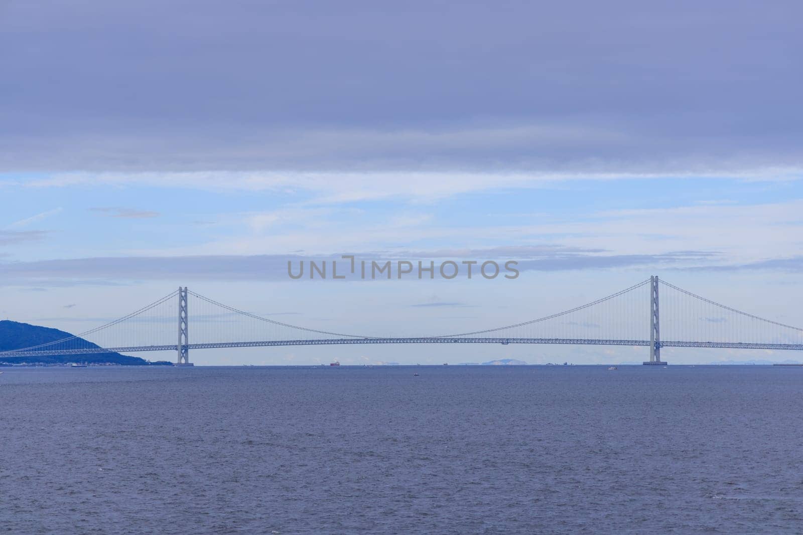 Low cloud layer over Akashi suspension bridge and calm blue water. High quality photo