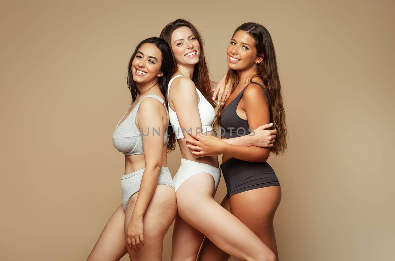 Group of glad millennial diverse women in underwear of different sizes motivation for self love, isolated on beige background, studio. Spa treatments, wellness or health, skin, natural beauty care
