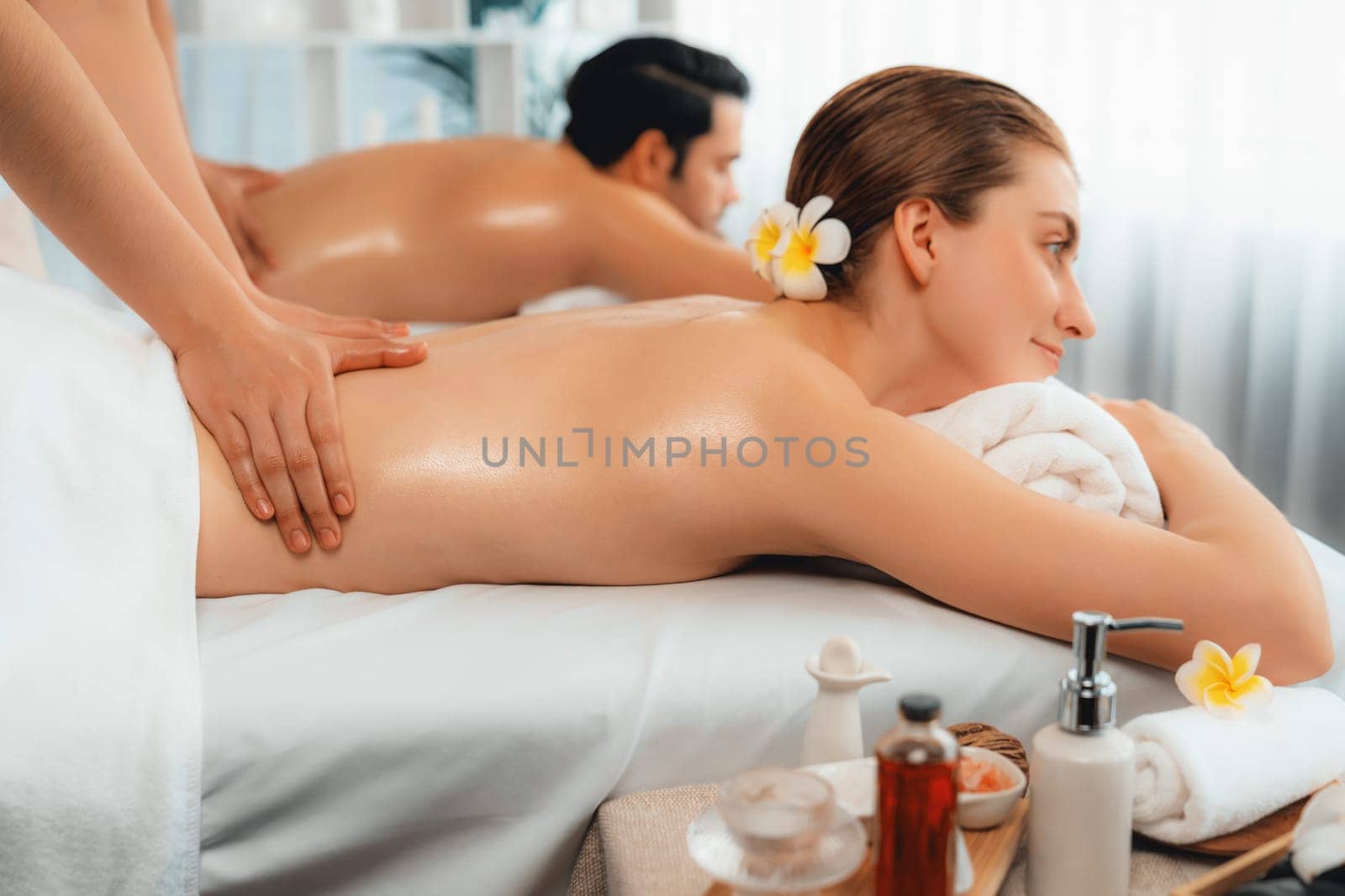 Caucasian couple customer enjoying relaxing anti-stress spa massage and pampering with beauty skin recreation leisure in day light ambient salon spa at luxury resort or hotel. Quiescent